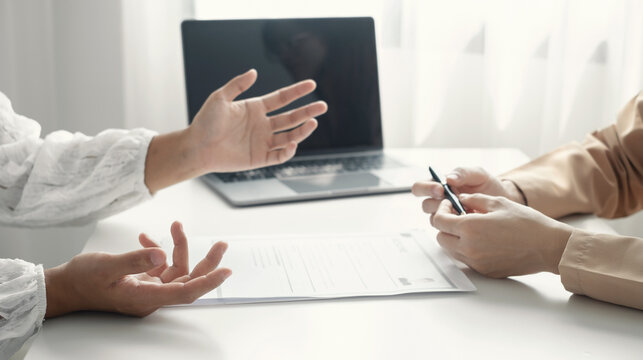 Job applicant explaining qualifications to manager during job interview with resume document and laptop at office desk concept