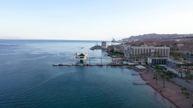 Aerial view of a sunny resort town on the Red Sea coast with hotels and a marina.