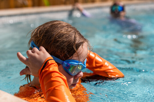 Young boy adjusting bright blue swimming goggles