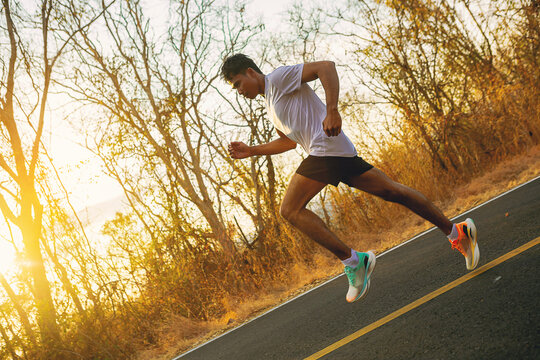 Silhouette of young man running sprinting on road. Fit runner fitness runner during outdoor workout with sunset background. selected focus