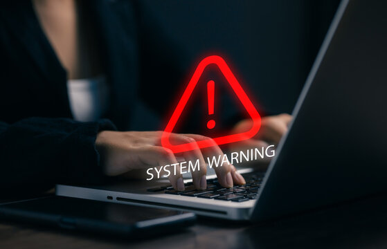 Business professional working on laptop with system warning alert, representing cybersecurity risk, technical error, data protection, online security, system failure, and digital safety.