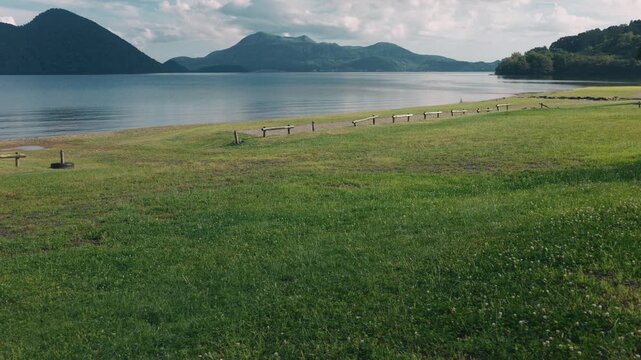 Lakeside grassy area with a distant view of Mount Usu across Lake Toya