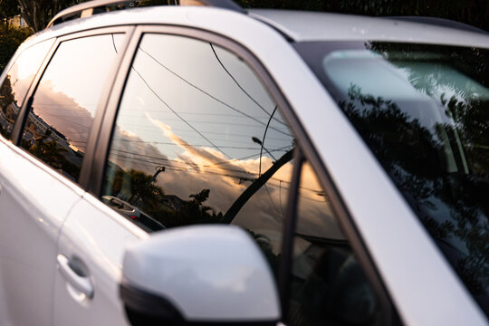 sunset sky reflected in the windows of a white car