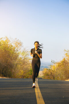 Silhouette of young woman running sprinting on road. Fit runner fitness runner during outdoor workout with sunset background. Selected focus