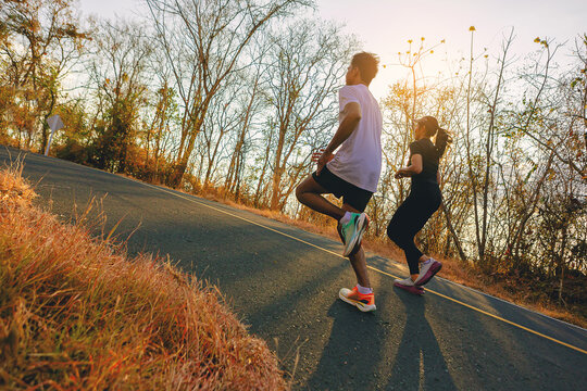 Silhouette of couple running together on road with sunset background.. Couple, fit runners fitness runners jogging together during outdoor workout.