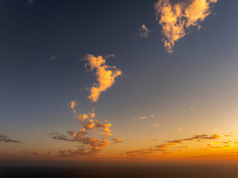 Golden hour clouds illuminate the sky above the ocean horizon