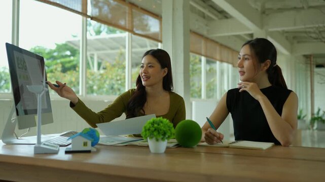 Two businesswomen discussing environmental social governance project and renewable energy in a modern office