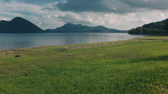 Lakeside grassy area with a distant view of Mount Usu across Lake Toya