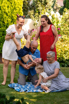 Family Laughing While Boy Plays Upside Down Outdoors