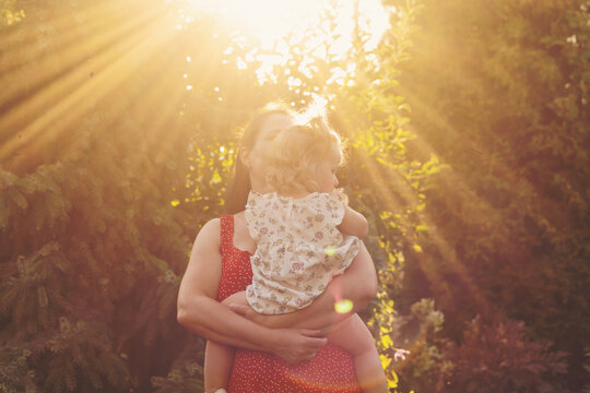 Mother Holding Toddler Daughter in Dramatic Golden Sunlight