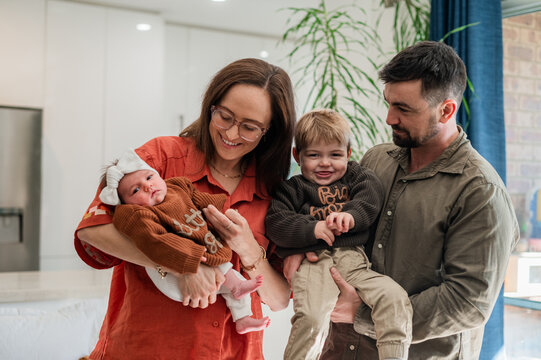 Parents hold their two children while smiling in a home setting with modern decor