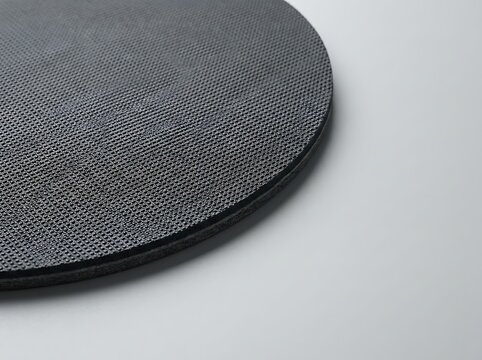 A close-up view of a black circle mouse pad on a grey surface showing the textured fabric surface