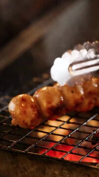 Grilling Thai Isan Sausages on Charcoal Grill with Tongs