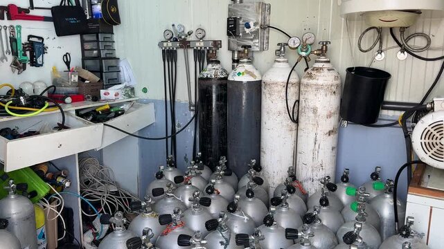 A large collection of scuba diving cylinders stored inside a dive center, showing tanks with valves and equipment ready for underwater diving activities and exploration.