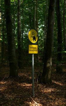 Yellow warning sign for a military training area with a soldier silhouette in a green forest in Denmark