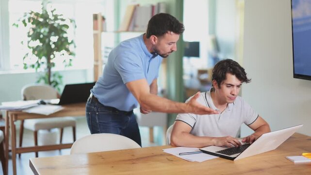 Guy helps man complete task on laptop, explains and shows how to work with software. Travel agency, regional representative office of international company, engineering company 