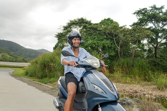 Young Cook Islander man riding a motorbike alone on a rural road in Far North Queensland