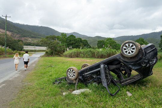 Couple walking away from an overturned car on the side of the road