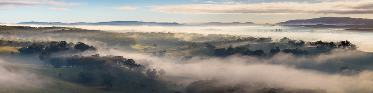 Morning mist blanketing rolling valleys beneath distant mountain horizons