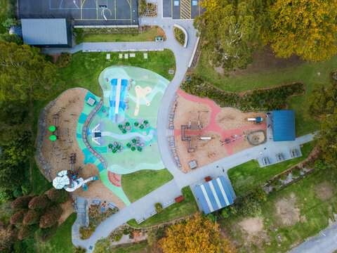 Aerial view of colourful community playground surrounded by parkland and trees