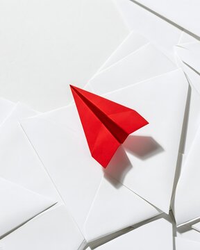 Rotes Papierflugzeug zwischen wei&szlig;en Fl&auml;chen als Symbol f&uuml;r Mut und neue Richtung