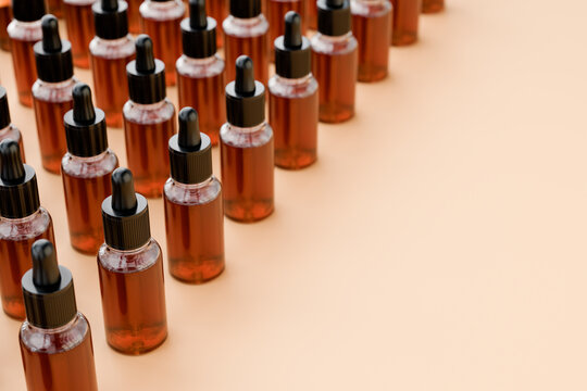 Amber glass dropper bottles filled with cosmetic or aroma essence liquid, black pipettes, arranged in rows beige background. Skincare, serum, laboratory and beauty product concept.	