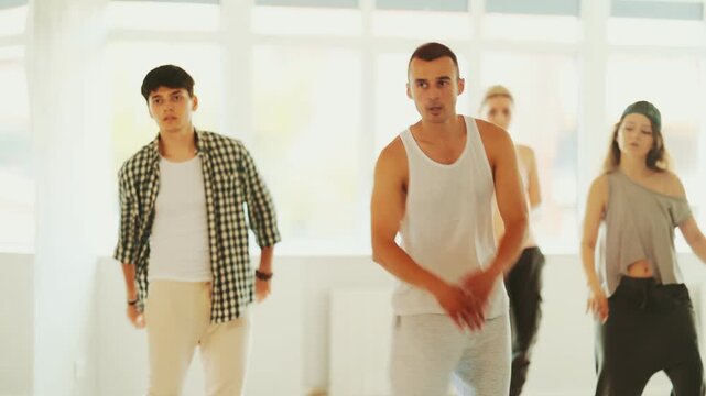 Dance group in casual clothes training to dance hip-hop and breakdance together in a dance center. High quality 4k footage