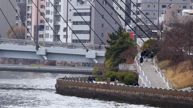 Pedestrians Walking Along Sumida River Waterfront in Tokyo Japan