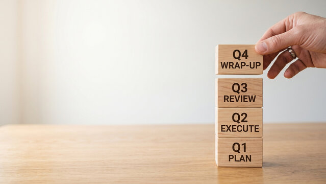 Hand stacking quarterly blocks showing plan, execute review and wrap up stages, representing annual business strategy planning cycle
