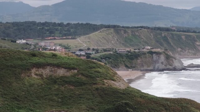Sopelana coast landscape with rugged cliffs, a sandy beach, and people enjoying the ocean waves in the Basque Country