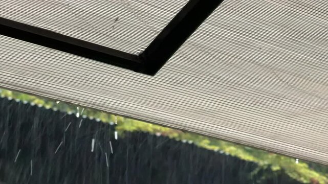 Water drop falling from polycarbonate roof edge close up macro concept for rain weather, house construction material, roof drainage system, waterproof protection, and green nature. High quality