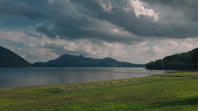Lakeside grassy area with a distant view of Mount Usu across Lake Toya