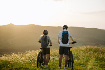 Fototapeta premium Senior couple at bike ride in nature, looking at sunset.