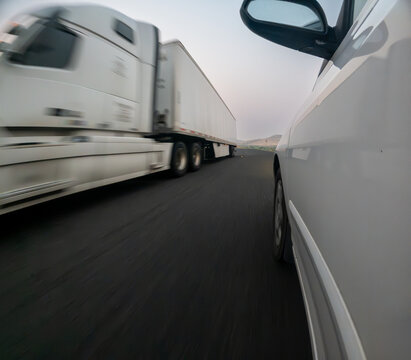 Highway scene showing a white semi-truck passing a car