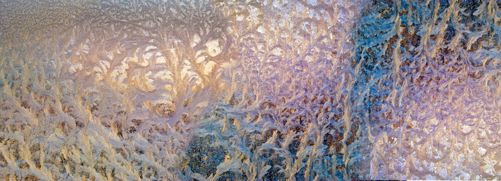 Frost patterns form on glass during a cold morning in winter