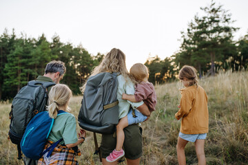 Naklejka premium Family hiking together through countryside during summer camping trip.