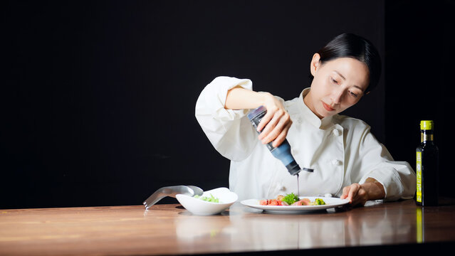 料理を盛り付ける女性シェフ。調理師、レストラン、飲食店、ディナー、サラダ、コース、フレンチ、美食