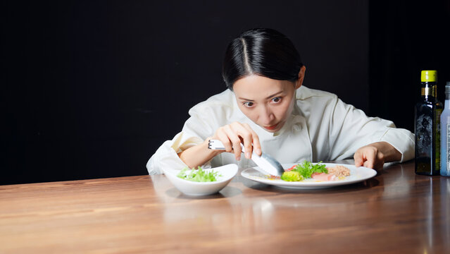料理を盛り付ける女性シェフ。調理師、レストラン、飲食店、ディナー、サラダ、コース、フレンチ、美食