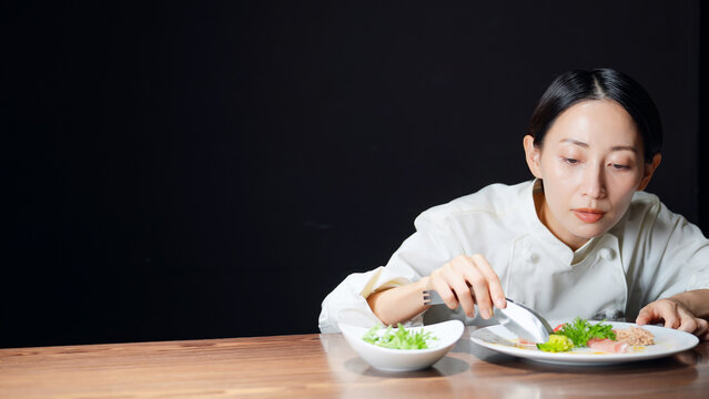 料理を盛り付ける女性シェフ。調理師、レストラン、飲食店、ディナー、サラダ、コース、フレンチ、美食