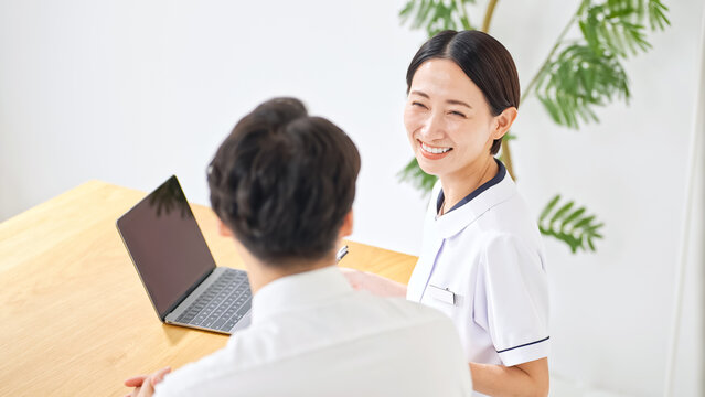 問診する白衣の女性。看護師、医師、産業医、相談、面談、診察、診療、健診、受付、クリニック、薬剤師