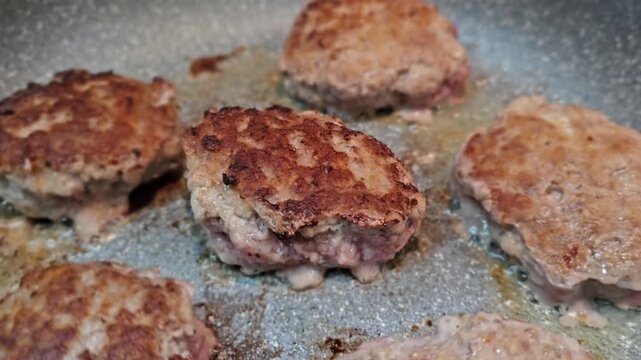Cooking meat patties in a pan with attention to texture and color