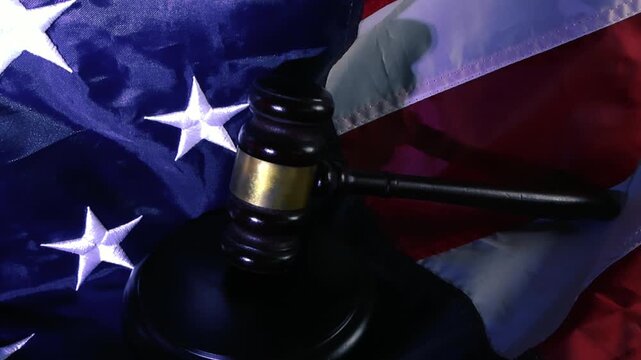Wooden judge gavel and sound block resting on the United States of America flag, symbolizing the concept of American law, judiciary system, government authority, and the rule of law in the USA