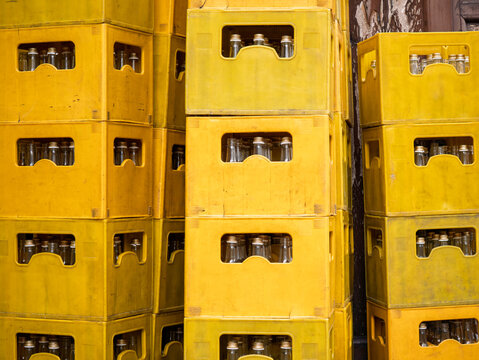 Reusable glass bottles in yellow beverage crates, returnable packaging, circular economy, recycling logistics, warehouse storage and sustainable distribution.