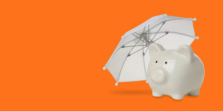 Insurance. Piggy bank sits under an umbrella against a vibrant background