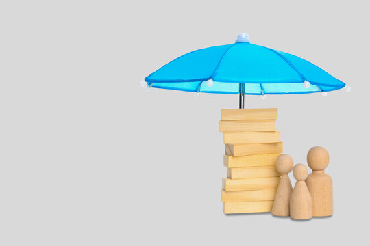 Insurance. Colorful umbrella stands over blocks and figures in a studio setting