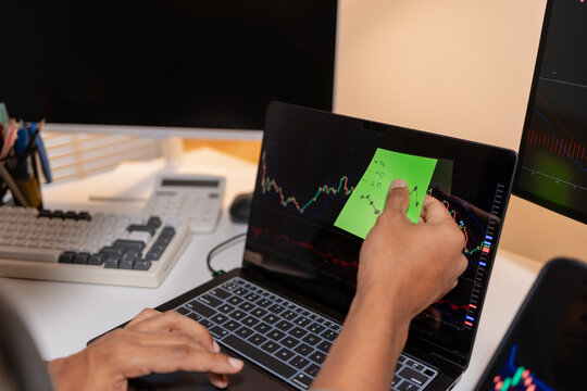 Professional stock trader reviewing market charts with sticky notes across multiple monitors, laptop, and tablet to analyze price trends, plan trading strategies, and manage investment decisions.