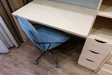 Light‑beige desk with open shelving and drawers. paired with plush blue upholstered office chair...
