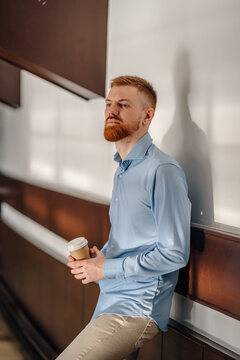 Ginger man holding coffee cup thinking and reflecting