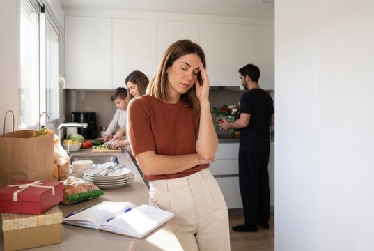 Stressed mother feeling overwhelmed with family activities and household tasks in kitchen