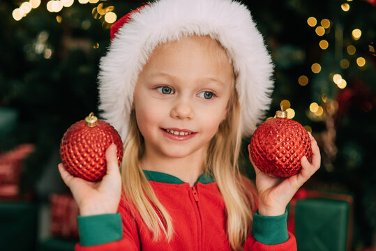 Merry Christmas and Happy Holidays. Child girl in Santa Claus hat with gifts under Christmas tree